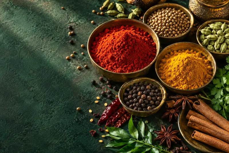 Colourful spices and whole ingredients on an emerald table